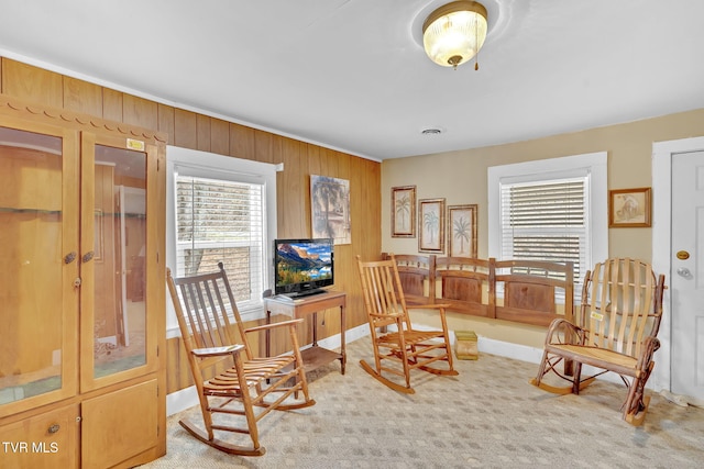 sitting room with baseboards, visible vents, wood walls, and carpet floors