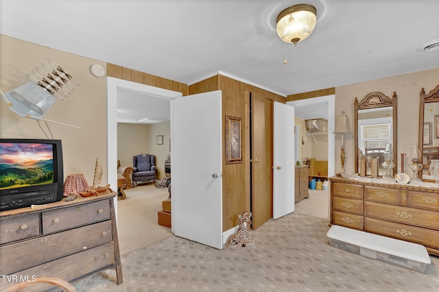 bedroom with wooden walls, light colored carpet, and visible vents