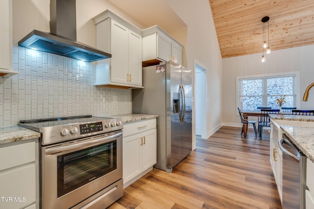 kitchen featuring light wood finished floors, appliances with stainless steel finishes, white cabinets, and wall chimney range hood