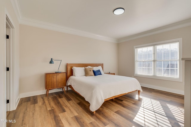 bedroom featuring baseboards, wood finished floors, and ornamental molding