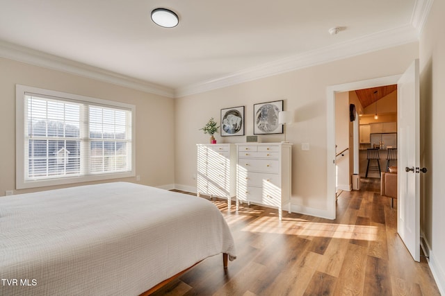 bedroom featuring baseboards, attic access, wood finished floors, and ornamental molding