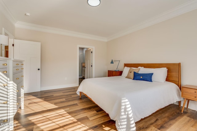 bedroom featuring ensuite bath, crown molding, baseboards, and wood finished floors