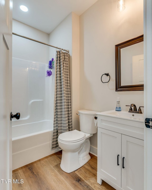 bathroom featuring toilet, wood finished floors, vanity, and shower / bath combination with curtain