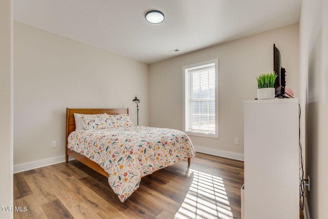 bedroom featuring visible vents, wood finished floors, and baseboards