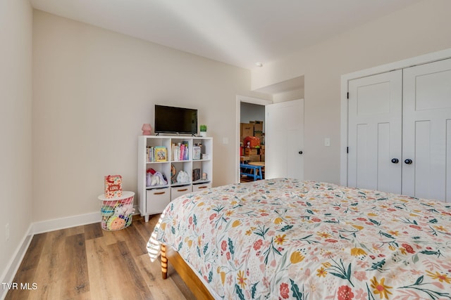 bedroom with a closet, baseboards, and wood finished floors