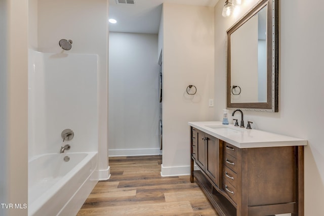 full bath with vanity, wood finished floors, visible vents, baseboards, and shower / tub combination