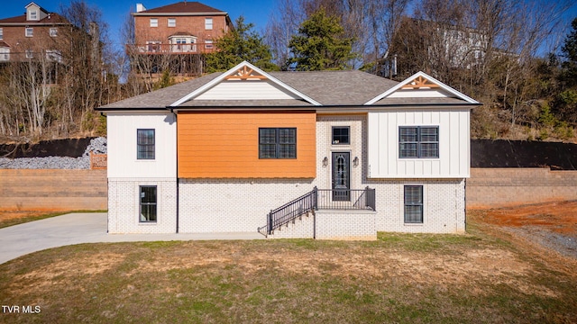 view of front of property with brick siding, board and batten siding, and a front yard