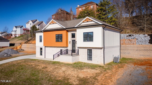 view of front of home featuring a front lawn, cooling unit, and brick siding