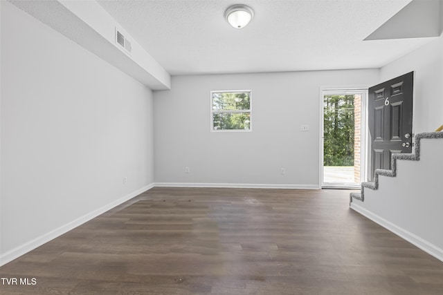 unfurnished room with a wealth of natural light, visible vents, and dark wood finished floors