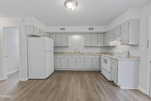 kitchen featuring white appliances, visible vents, under cabinet range hood, and a sink