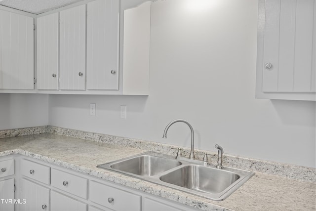 kitchen with light countertops, white cabinets, and a sink