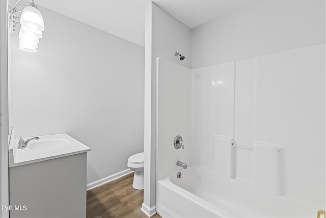 full bath featuring baseboards, toilet, shower / bathing tub combination, wood finished floors, and vanity