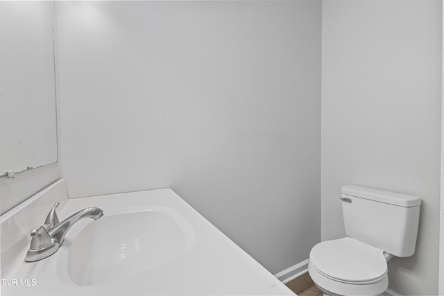 bathroom with toilet, baseboards, and a sink