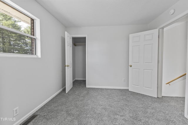 unfurnished bedroom featuring carpet flooring, a textured ceiling, and baseboards