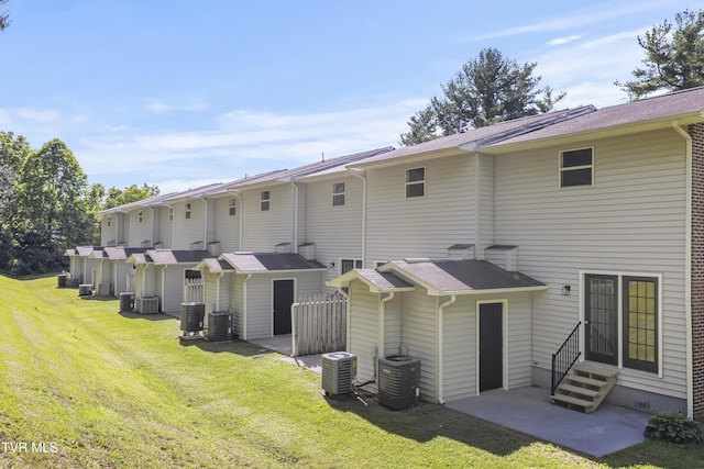 back of house with central air condition unit, entry steps, and a yard