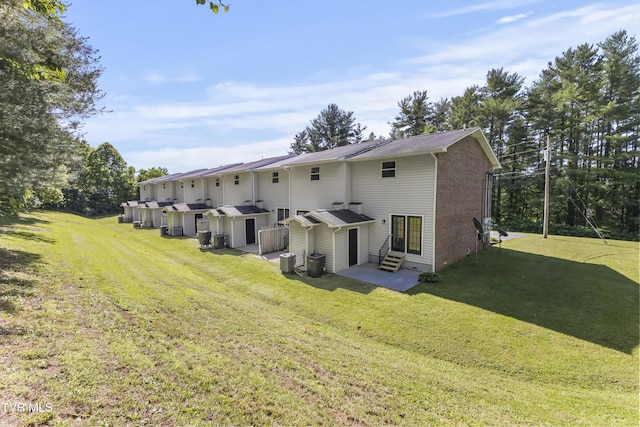 rear view of house featuring entry steps, a yard, central AC unit, and brick siding