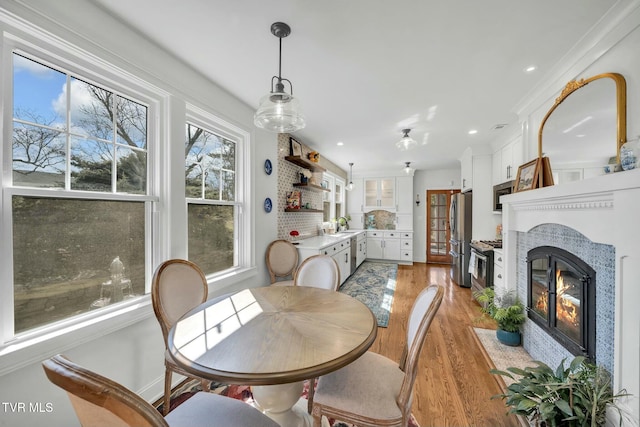 dining room featuring recessed lighting, a fireplace with flush hearth, and light wood-style flooring