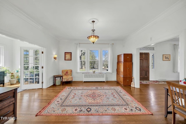 interior space with radiator, crown molding, baseboards, and wood finished floors