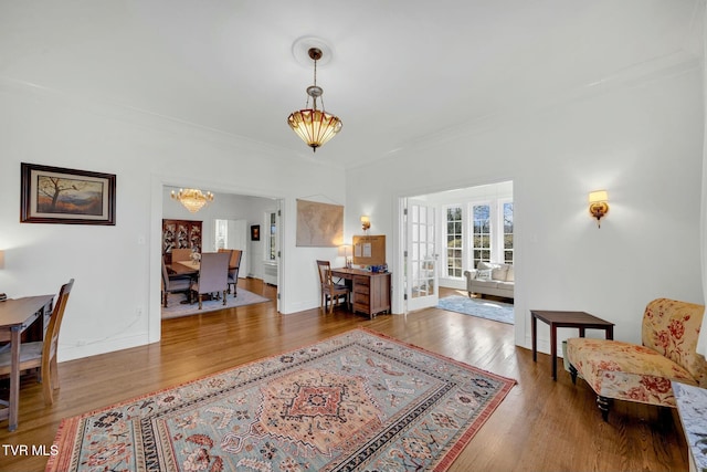 interior space with a notable chandelier, wood finished floors, french doors, crown molding, and baseboards