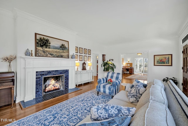 living room featuring a fireplace, wood finished floors, and ornamental molding