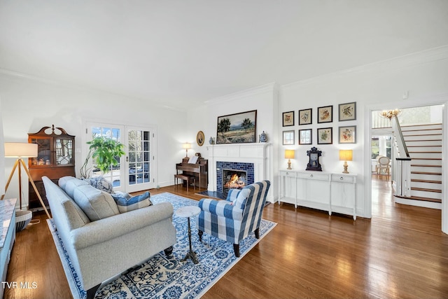 living area featuring stairs, crown molding, wood finished floors, and a tile fireplace