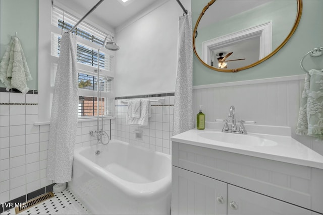 full bath featuring ceiling fan, a shower with shower curtain, a bathtub, wainscoting, and tile patterned floors