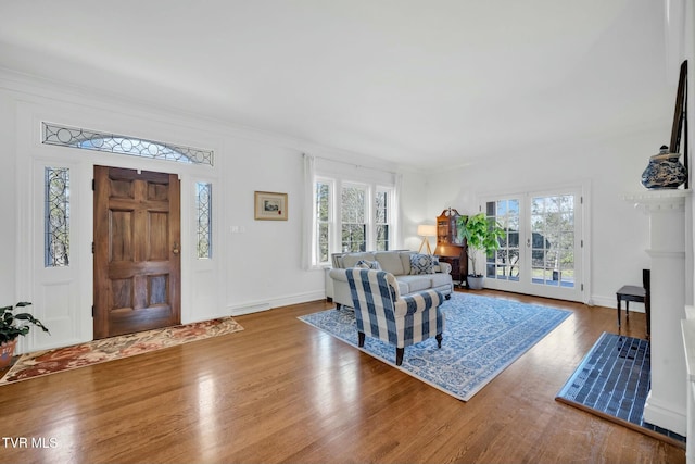 living room featuring crown molding, wood finished floors, baseboards, and a wealth of natural light