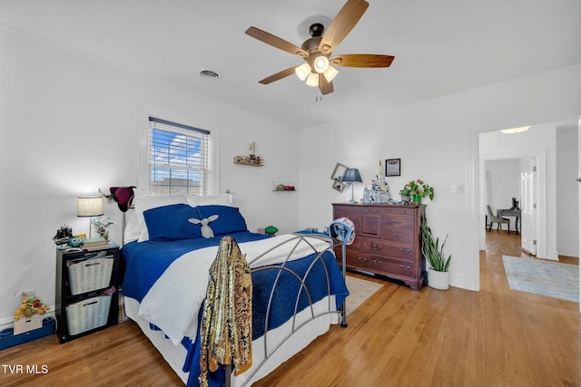 bedroom featuring baseboards, a ceiling fan, visible vents, and light wood-type flooring