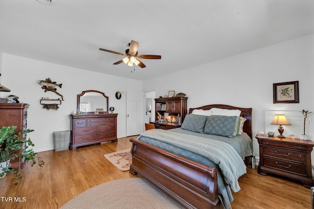 bedroom featuring baseboards, wood finished floors, and a ceiling fan