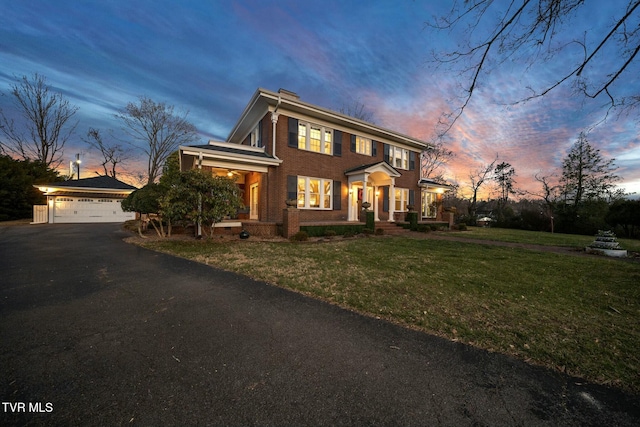 colonial inspired home featuring brick siding, a detached garage, and a yard