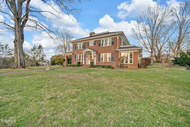 view of front of home featuring a front lawn, brick siding, and a chimney