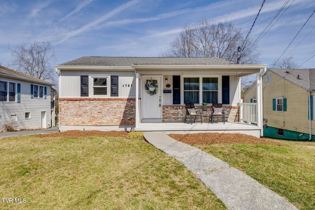 view of front of house featuring board and batten siding, a front yard, covered porch, and brick siding