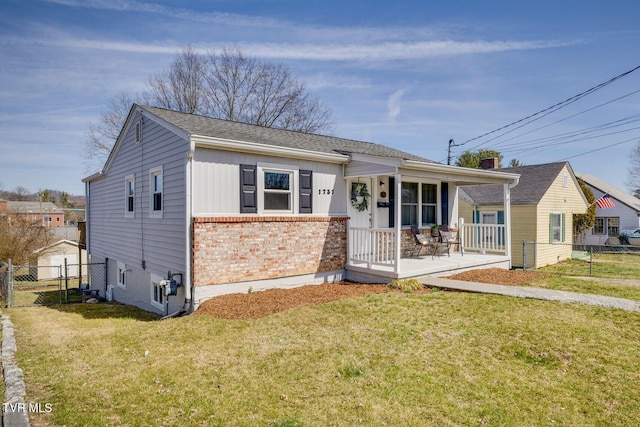 view of front of home with brick siding, board and batten siding, a front lawn, fence, and covered porch