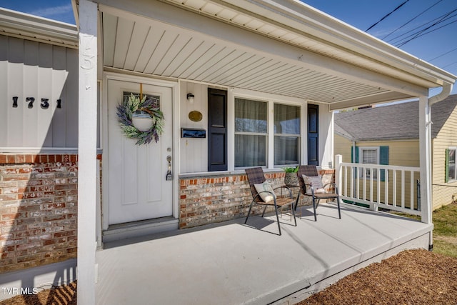 entrance to property featuring board and batten siding, brick siding, and covered porch