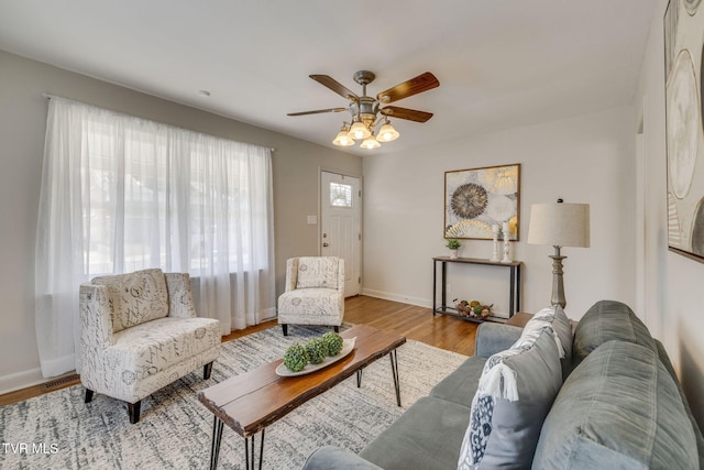 living area featuring a ceiling fan, wood finished floors, and baseboards