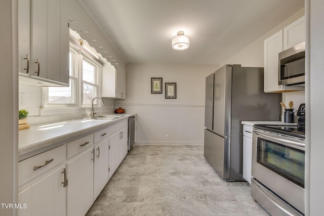 kitchen with a sink, white cabinetry, appliances with stainless steel finishes, light countertops, and baseboards