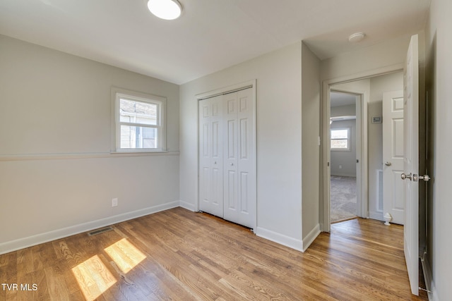 unfurnished bedroom featuring visible vents, light wood-type flooring, and baseboards