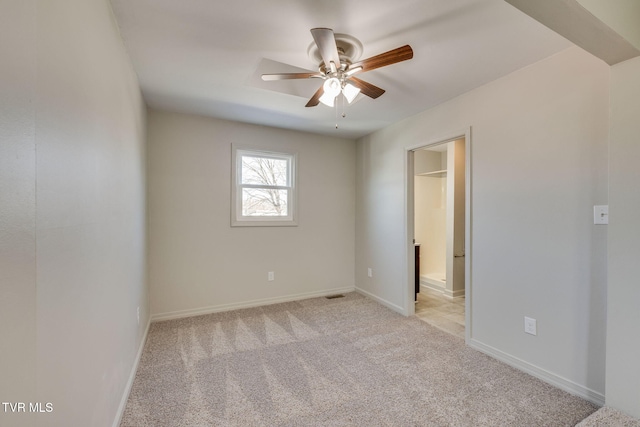 spare room with light carpet, baseboards, and ceiling fan