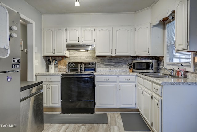 kitchen with under cabinet range hood, stainless steel microwave, a sink, black / electric stove, and white cabinets