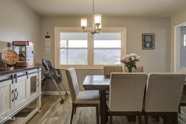 dining space with baseboards, light wood-type flooring, and a chandelier