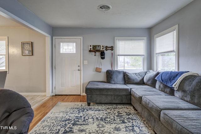 living area featuring visible vents, baseboards, and wood finished floors