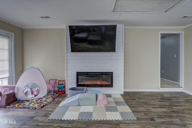 game room featuring wood finished floors, a fireplace, crown molding, baseboards, and attic access