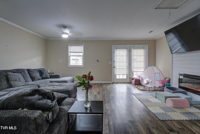 living room with wood finished floors, a large fireplace, crown molding, baseboards, and ceiling fan