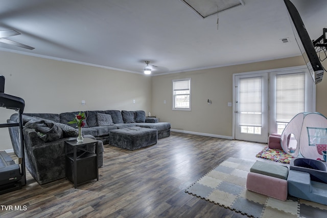 living area with attic access, wood finished floors, a ceiling fan, and crown molding