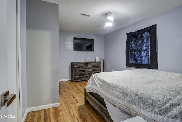 bedroom with visible vents, baseboards, and wood finished floors