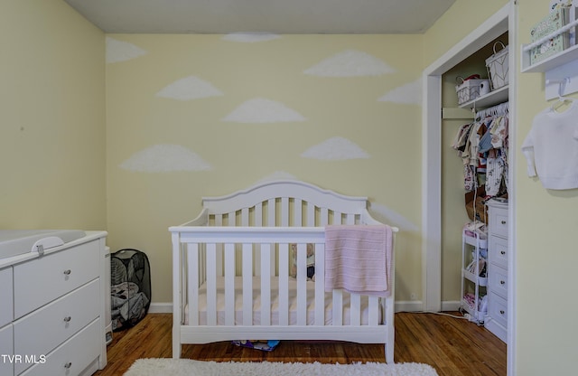 bedroom featuring a crib, baseboards, and wood finished floors