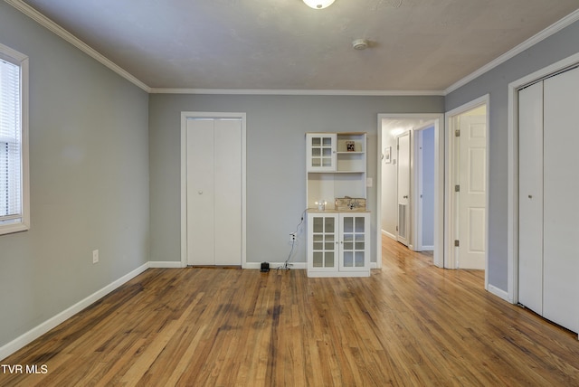 unfurnished bedroom with crown molding, wood finished floors, and baseboards