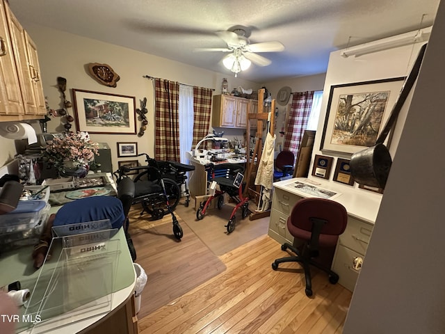 home office featuring light wood-style floors, ceiling fan, and a textured ceiling