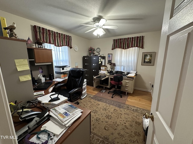 home office with light wood-type flooring and ceiling fan