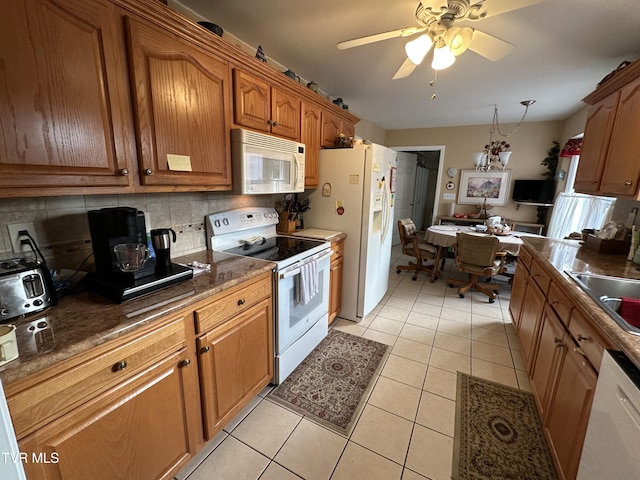 kitchen with brown cabinets, dark countertops, tasteful backsplash, white appliances, and light tile patterned floors